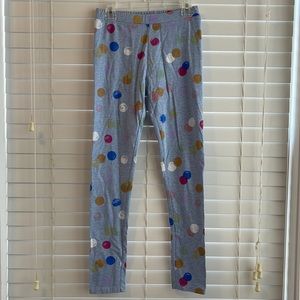 The brand is Gymboree. The size is 10-12. Gray pants with colorful polkadots.